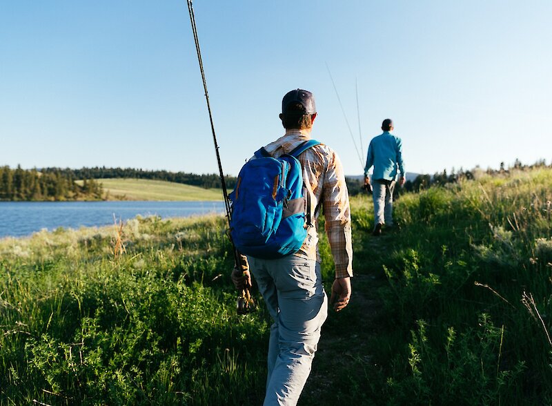 Two anglers carrying fly fishing rods walking towards Jacko Lake near Kamloops, BC.