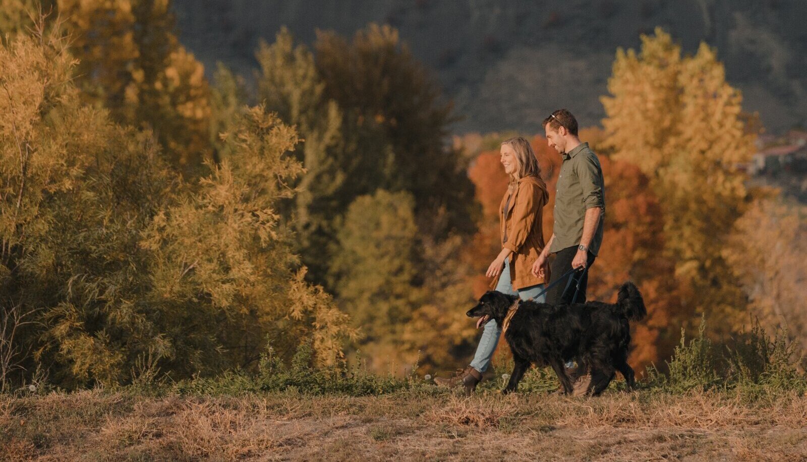A young couple walks with their dog through the scenic fall season colours in Kamloops.