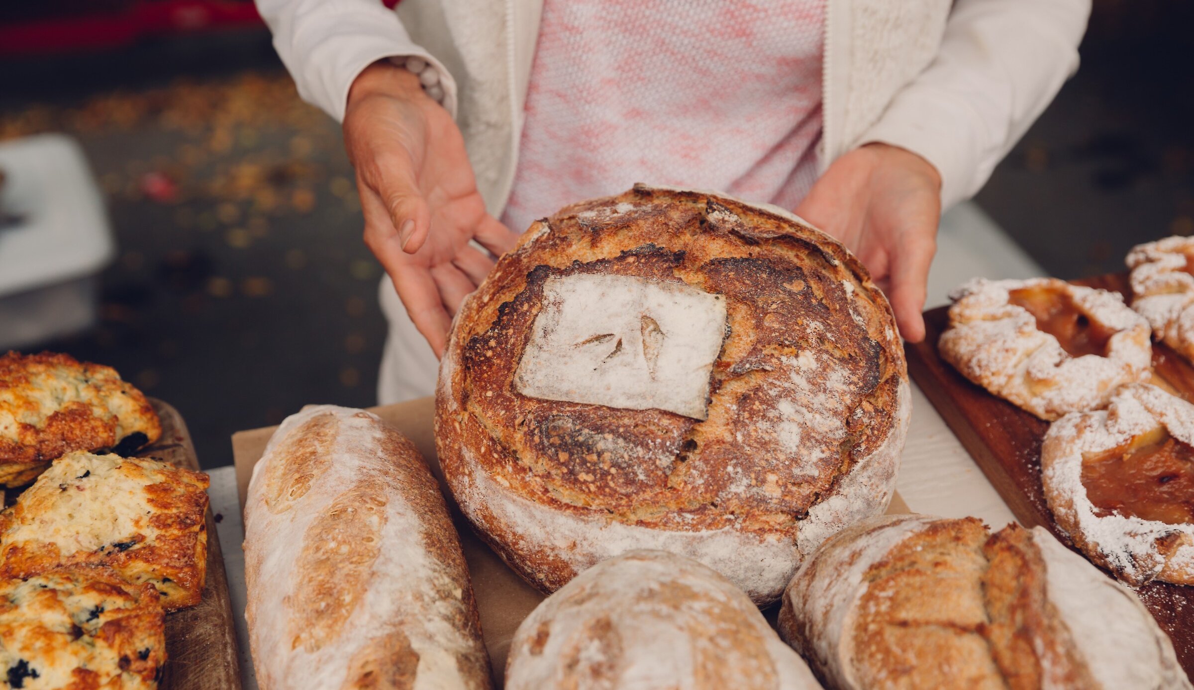 A baker at the Kamloops Farmers Market presenting a loaf of bread.