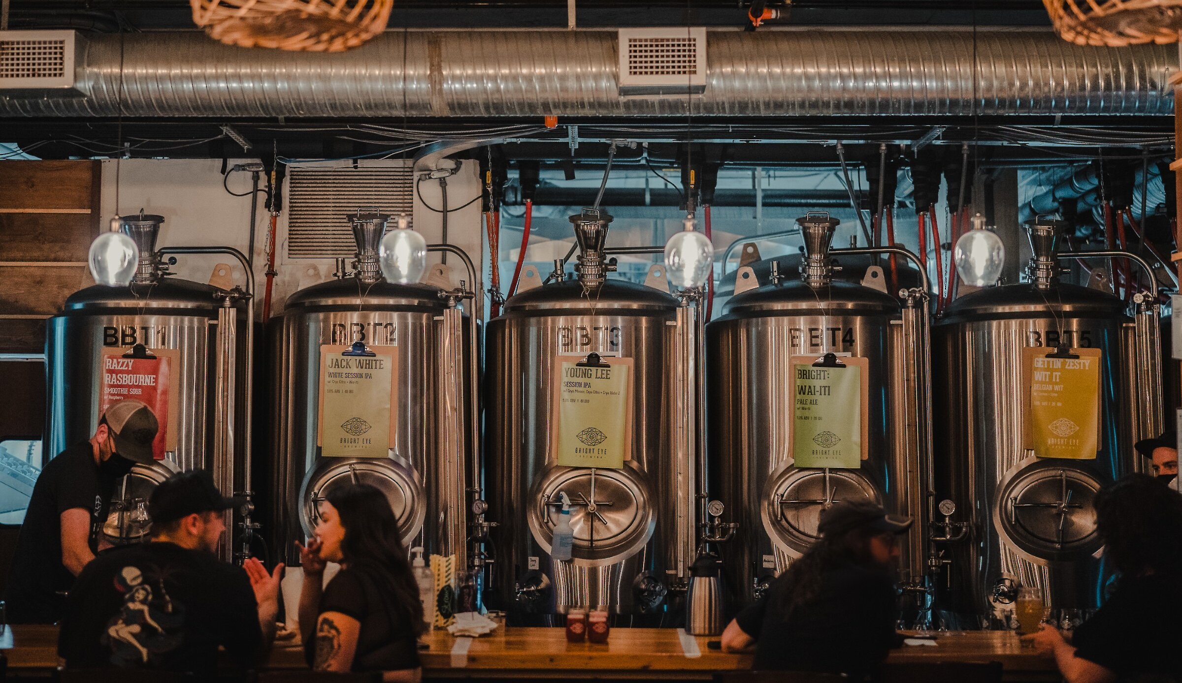 Guests sit at the bar enjoying their craft beer in front of the Brewery tanks at Bright Eye Brewing in Kamloops, BC.