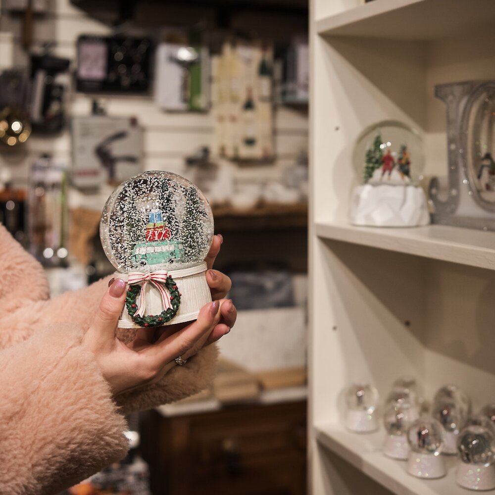 Shopper holding a Christmas Snowglobe at Castles and Cottages in Kamloops, BC.