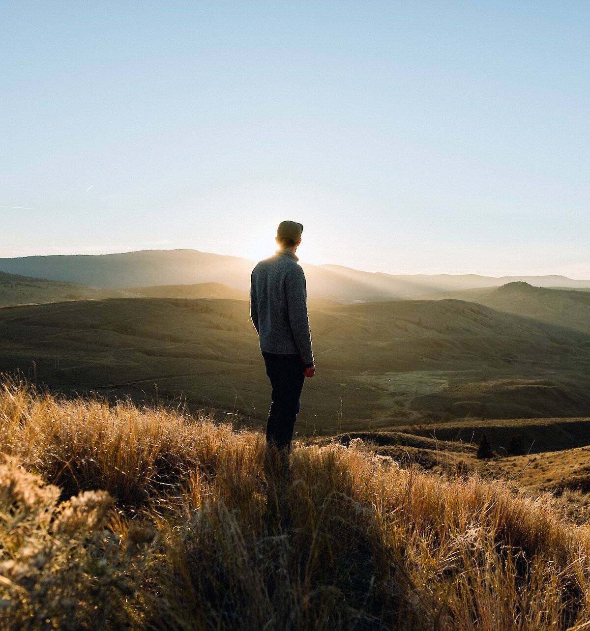 Hiker standing the grasslands of Kenna Cartwright Park admiring the view over the Thompson Valley in British Columbia.