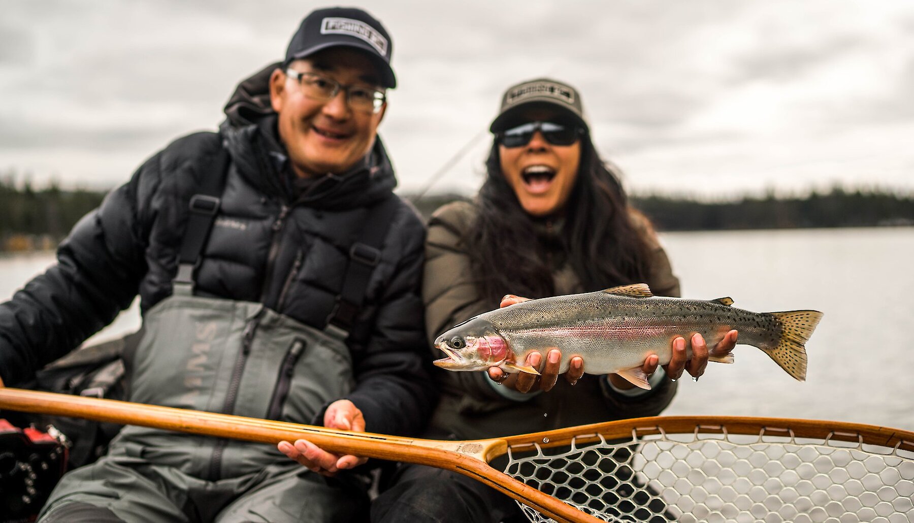 Two anglers lake fishing holding a rainbow trout and fishing net in Kamloops, BC.