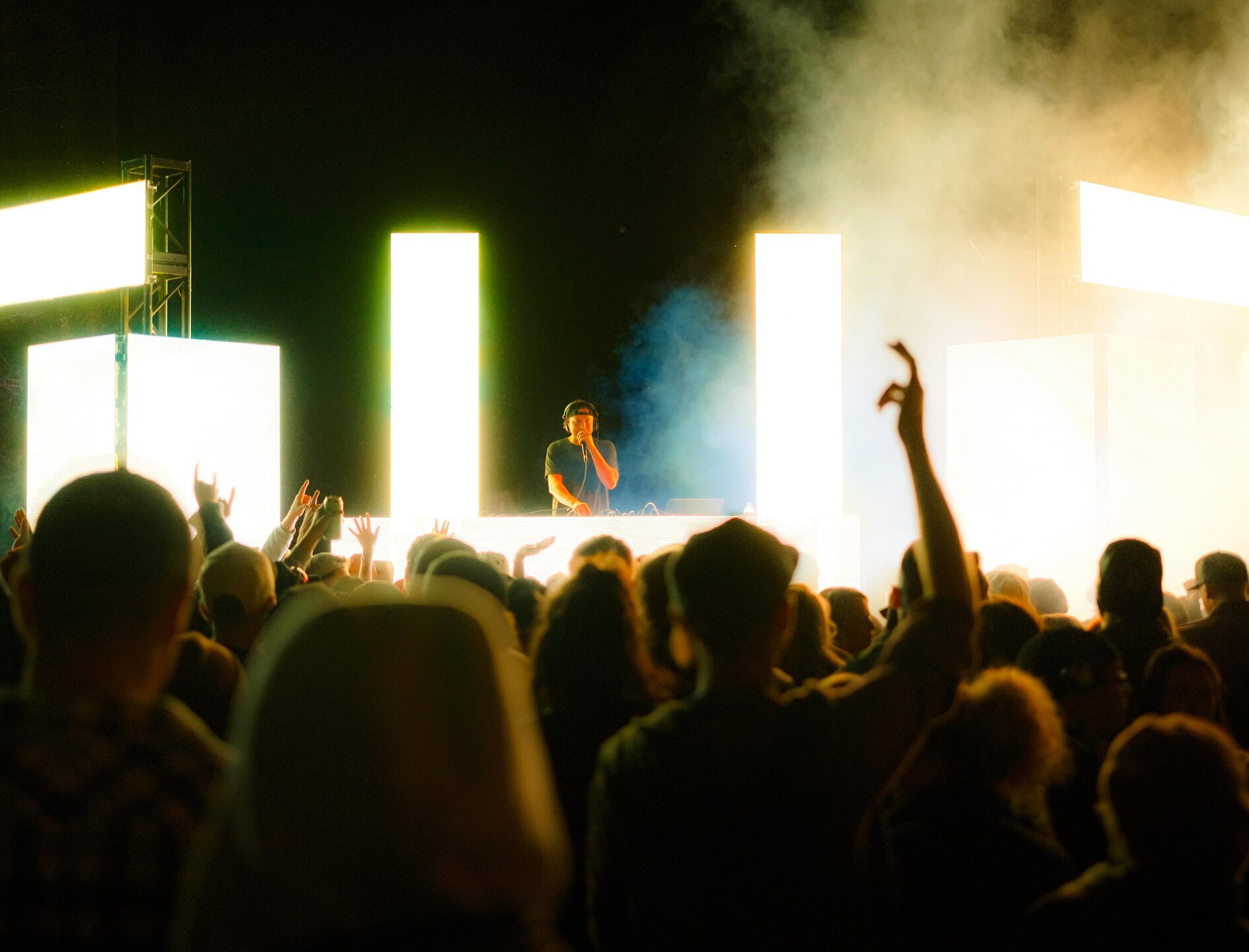 A DJ on stage with bright lights in front of a cheering crowd at Brewloops festival in Kamloops, BC.