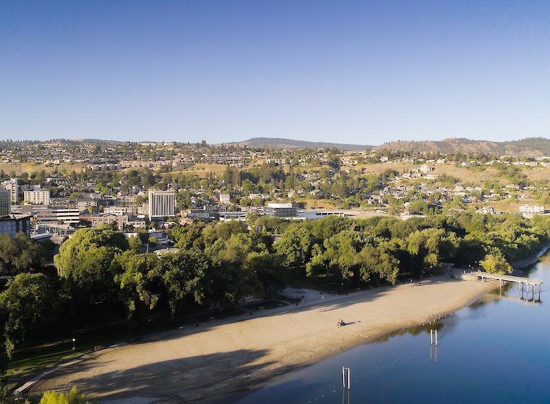Aerial view of sandy beach and treed shoreline at Riverside Park in Kamloops.