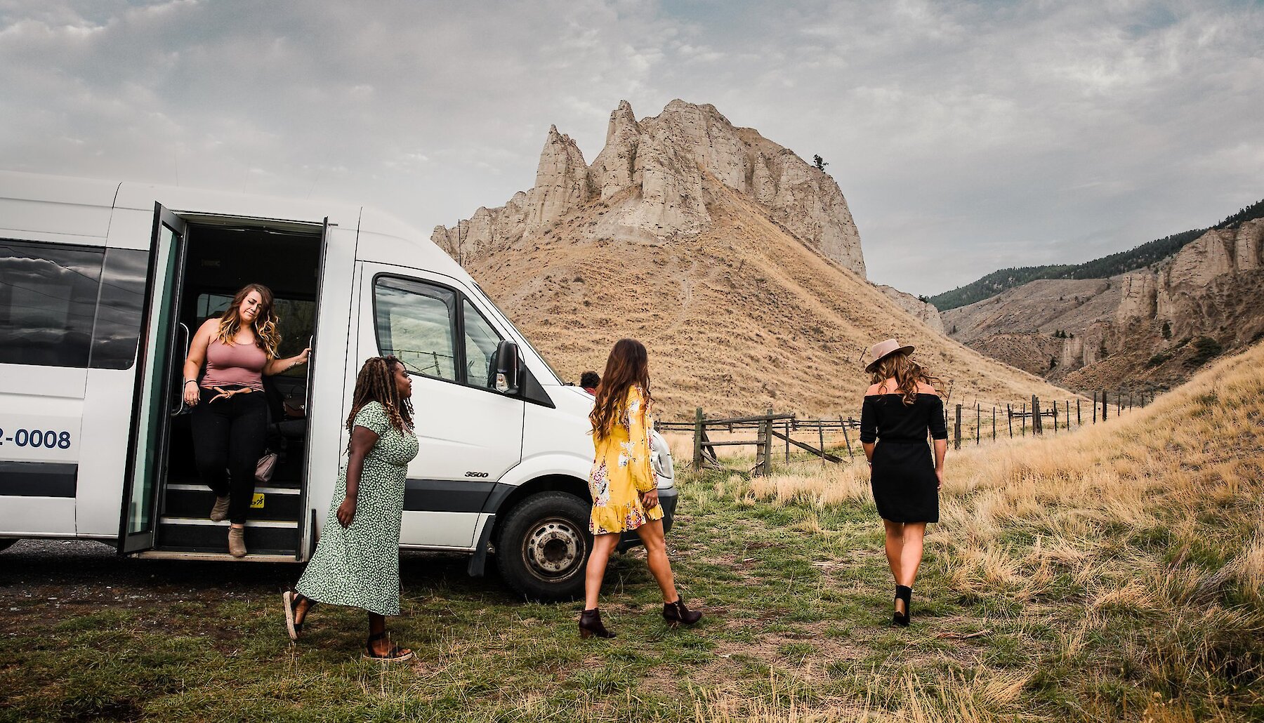 A group of women exiting the Divine Tours van on their Kamloops Winery Tour with a view of the iconic hoodoos in the background.